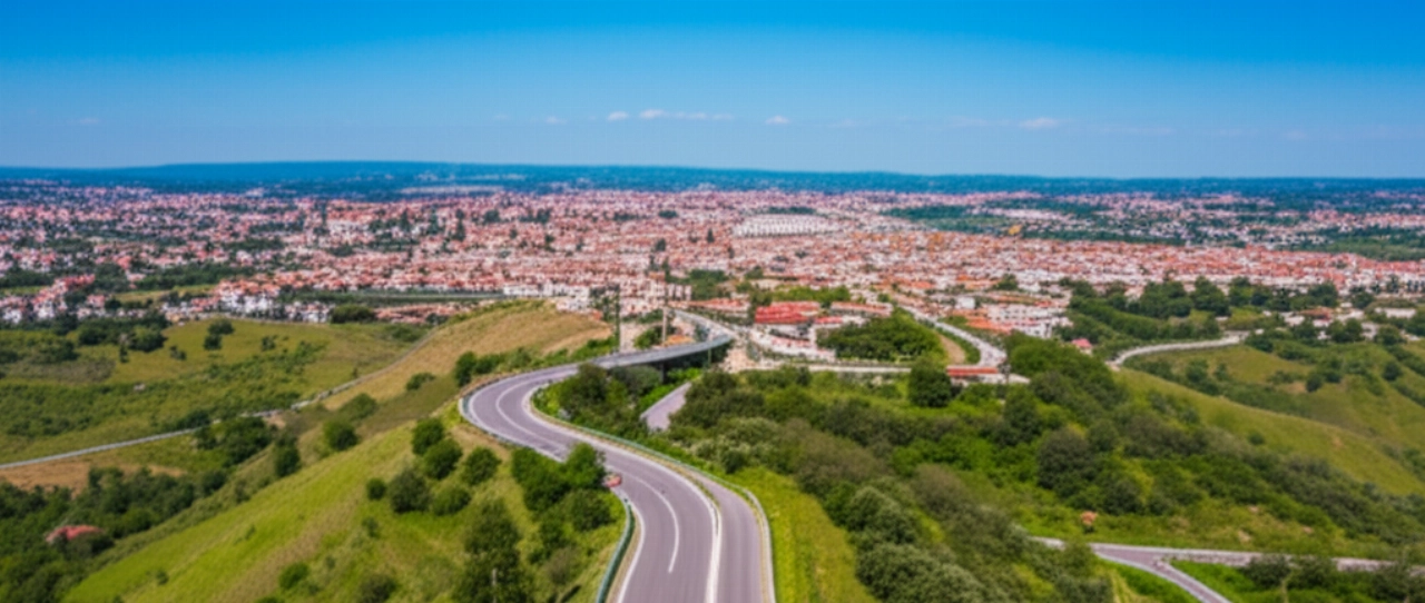 Vista aerea di un camion per traslochi che percorre una strada panoramica vicino a Benevento, con la città e le colline sullo sfondo.