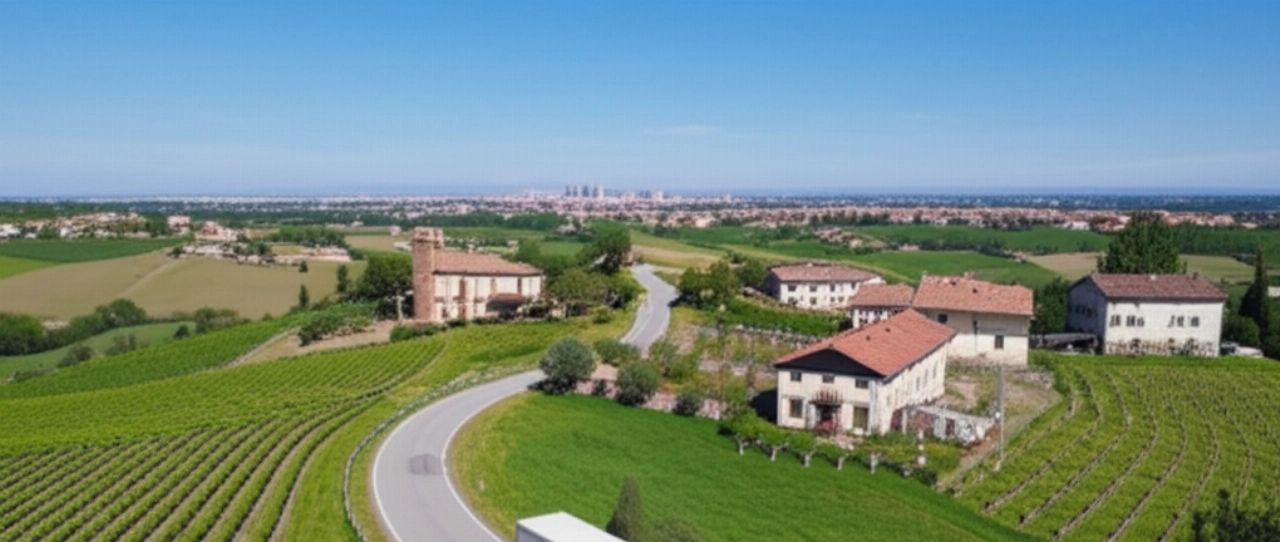 Vista aerea di un camion per traslochi che attraversa la campagna modenese, con la città all'orizzonte.